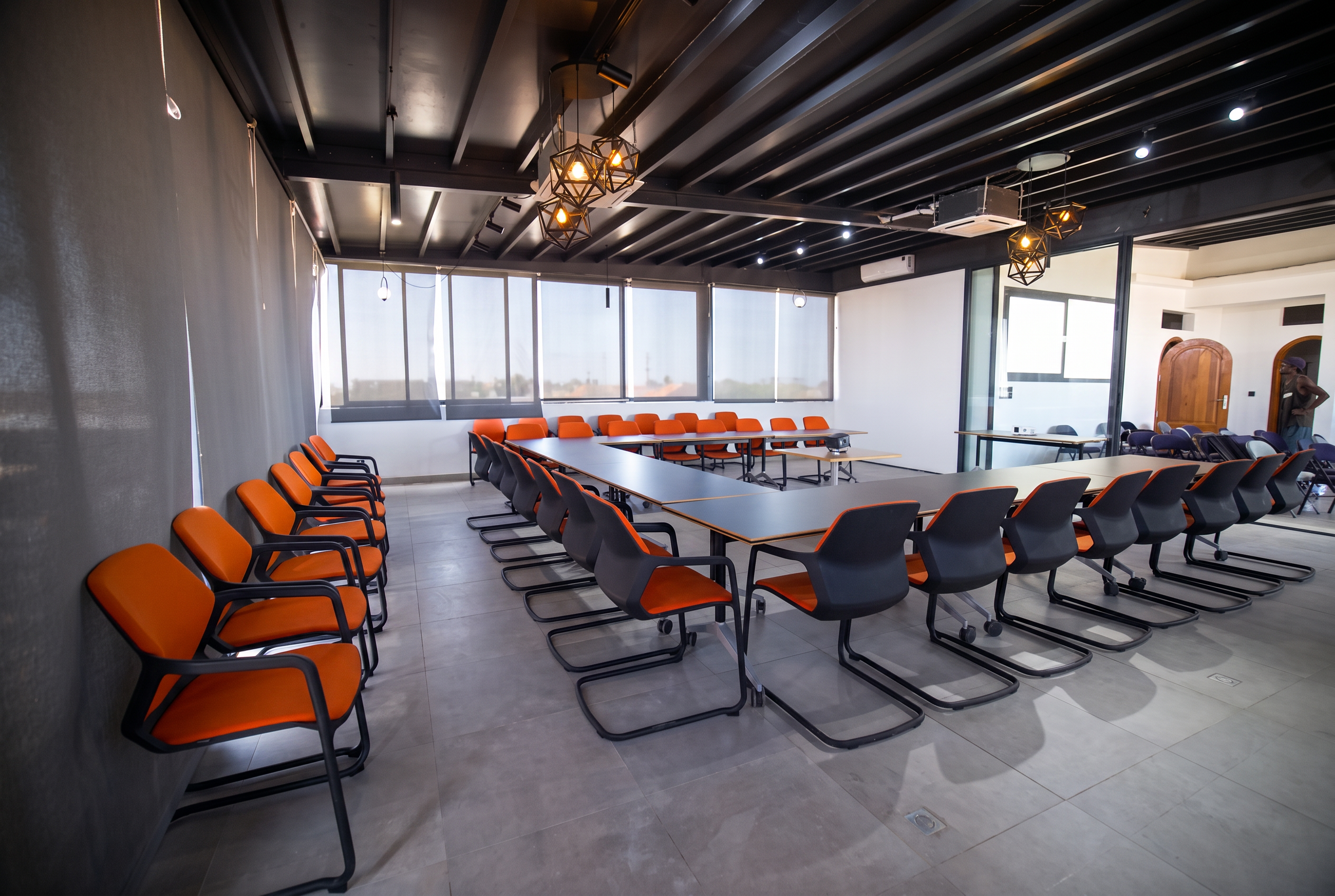 Open space de travail avec grandes tables et fauteuils orange